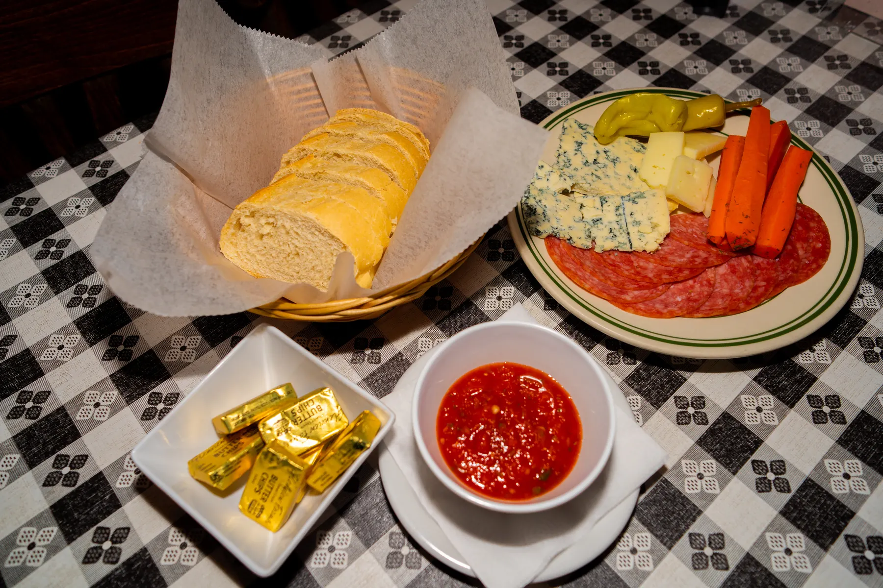 Antipasto plate with cured meat, cheese, peppers, carrots, bread, and salsa